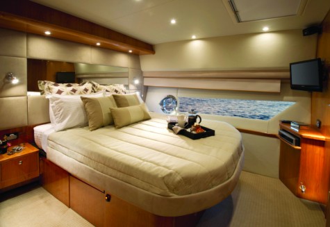 The master stateroom with hull window is luxuriously appointed with plenty of storage for extended voyages. Shown here in high gloss cherry cabinetry